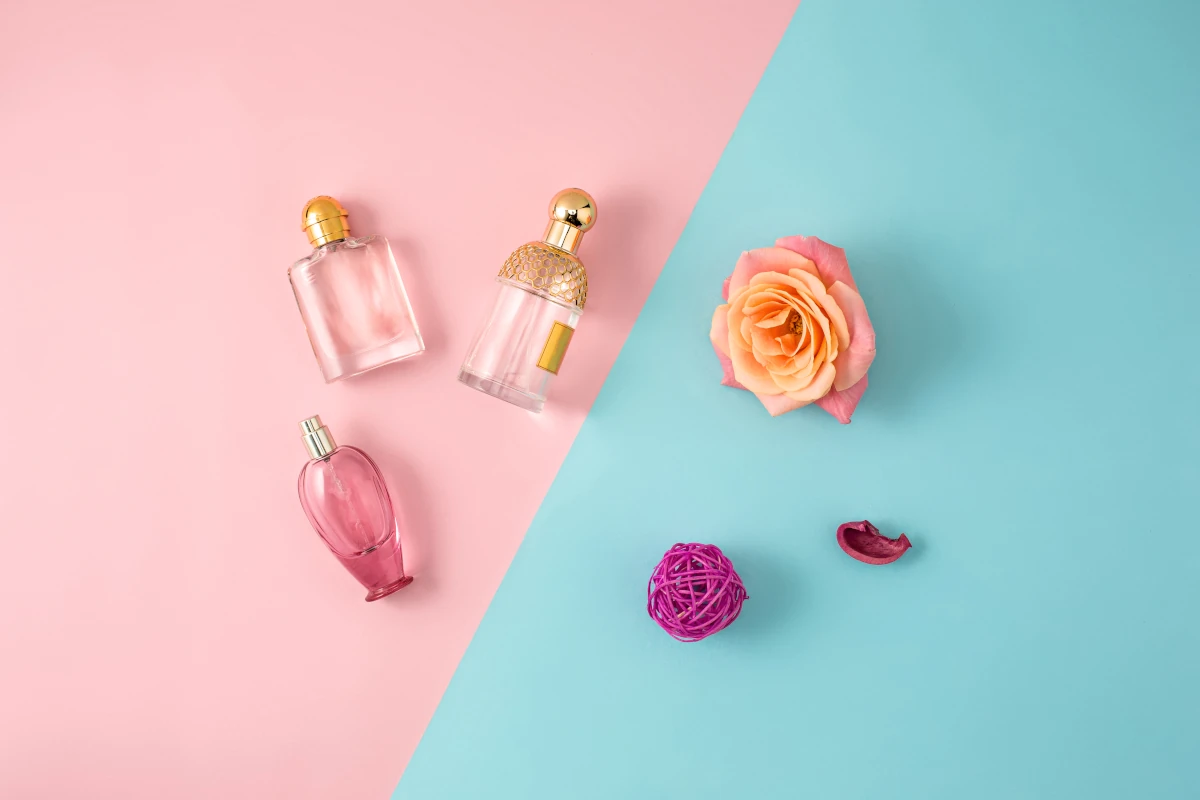buteleczki perfum i kwiaty na pastelowym tle