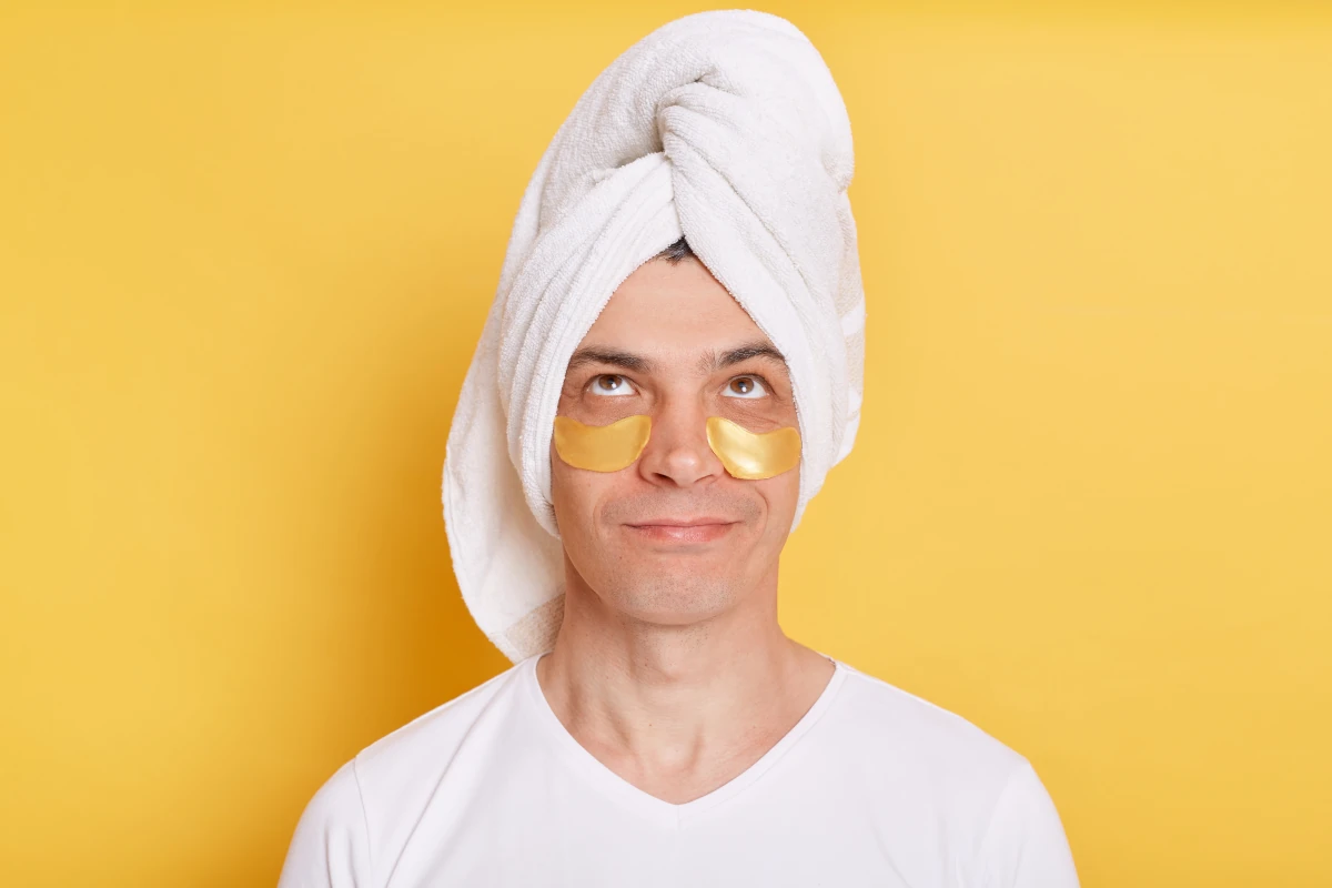 mężczyzna z maseczką pod oczami i ręcznikiem na głowie